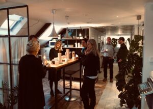 Företagspersonal minglar runt ett köksbord med kaffekoppar i det ljusa och välkomnande köket på Kontoret vid Österport, ett kontorshotell i Visby.