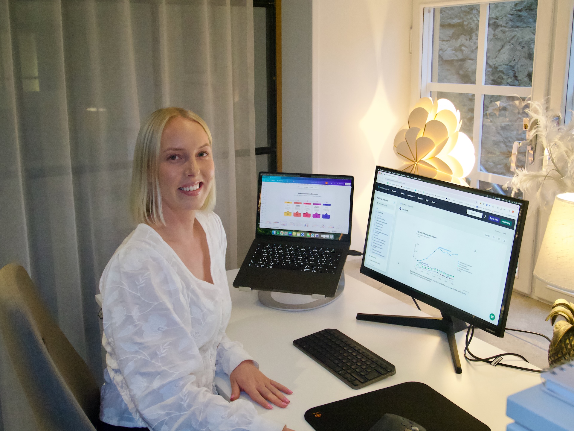 Linnéa sitter vid sitt skrivbord på Kontoret vid Österport i Visby, med två datorskärmar framför sig och ett leende mot kameran. På skärmarna syns material kopplat till digitala utbildningar, vilket speglar hennes arbete som utbildare och marknadsförare.